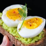 sliced egg on top of green salad with bread